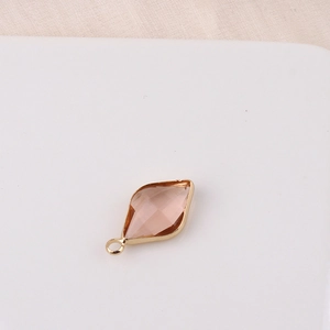 Detail of a rhombus-shaped gold pendant featuring a faceted pink crystal for DIY jewelry making
