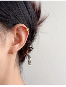 Macro side view of a model wearing golden jagged S925 silver ear studs and ear cuff set