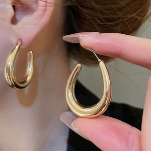 Close-up of chunky gold C-shaped hoop earrings with polished mirror finish on model