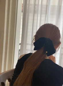Detail von elegantem schwarzem Samt-Schleifen-Haarclip mit goldenem Anhänger am Modell