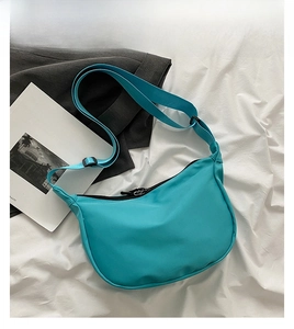 Detail view of a blue nylon crescent bag with adjustable strap in a lifestyle setting