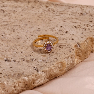 Detail view of gold adjustable ring with oval purple gemstone and halo zircon settings