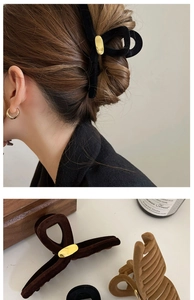 Détail de pinces à cheveux floquées en noir et marron avec des boucles ovales en métal doré