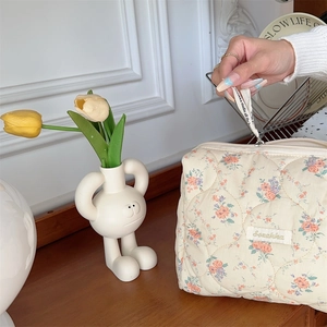 Detail of floral quilted cosmetic bag featuring a smooth zipper and brand ribbon tag