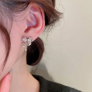 Elegant silver bow earrings with zircon star pendants and delicate beaded tassels on ear