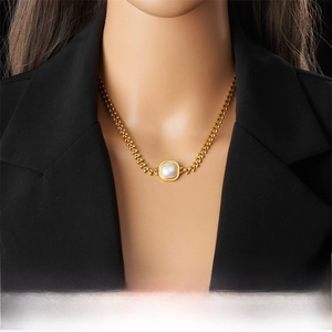 Close-up of a vintage gold-plated chain necklace with a square pearl pendant on a model