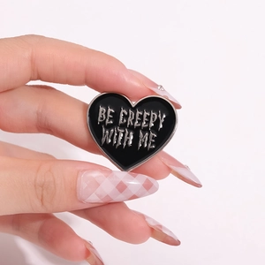Heart-shaped black enamel pin with Be Creepy With Me text for backpacks and jackets