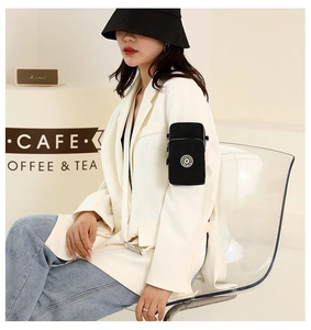 Close-up of a black nylon crossbody phone bag worn as a stylish arm band accessory