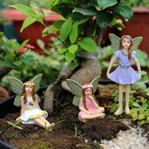 Detailed view of three miniature resin flower fairies in white, pink and purple dresses