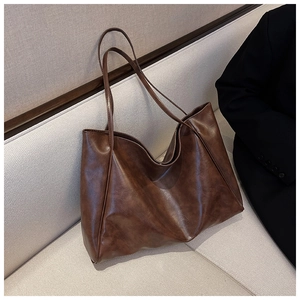 Close-up of vintage brown large capacity PU leather tote bag on a neutral sofa