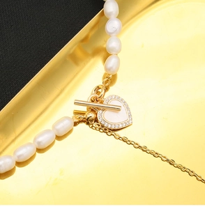 Detail of natural freshwater pearl necklace featuring a golden heart pendant and OT clasp