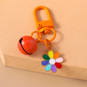 Macro shot of orange hook, red bell, and rainbow daisy flower keychain accessory