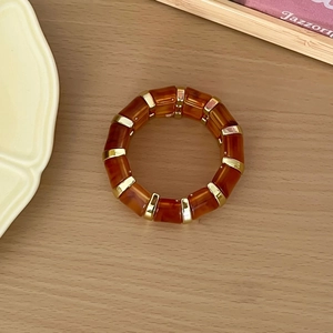 Vue détaillée d'un bracelet élastique en résine ambrée avec détails dorés sur bois