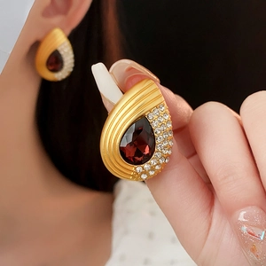 Macro detail of vintage teardrop earrings with burgundy gemstones and crystal pavé