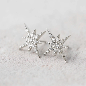 Primer plano de pendientes de estrella de ocho puntas en plata con circonitas brillantes