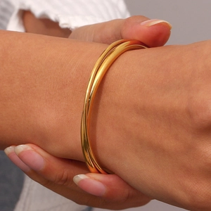 Detail showing elegant gold twisted bangle on wrist with a minimalist layered design