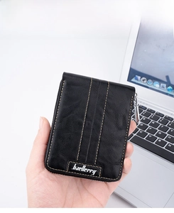 Close-up of black leather men's wallet with yellow stitching and metal zipper detail