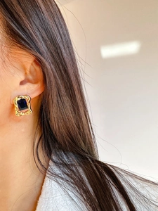 Detail view of model wearing vintage gold earrings with large blue zircon stones