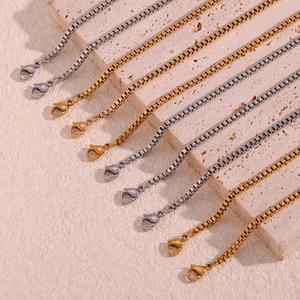 Detailed view of gold and silver stainless steel box chains with lobster clasps on stone