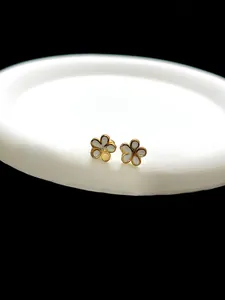 Close-up of elegant gold and white five-petal flower stud earrings on display