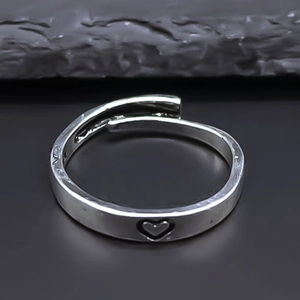 Adjustable silver heart cut-out ring on grey rock background, minimalist jewelry for couples