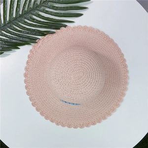 Vue de dessus d'un chapeau de paille rose pour enfants avec marguerite bleue décorative