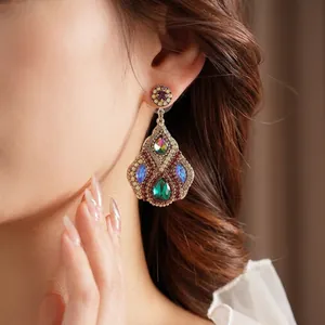 Vintage gold teardrop earrings with colorful crystals and zircons on a model