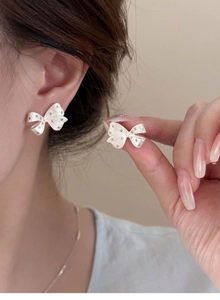 Close-up of sparkling silver bow earrings featuring detailed texture and micro-inlay accents