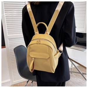 Detailed back view of a yellow leather mini backpack worn over a black jacket