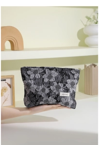 Détail d'une trousse de maquillage jacquard à fleurs tenue à la main avec décor