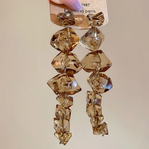 Detail of amber irregular acrylic earrings with tiered crystal blocks and silver pins