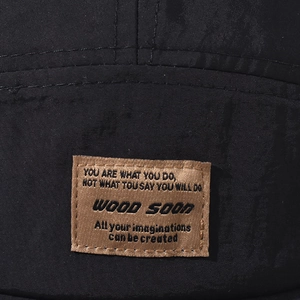 Close-up of fabric texture and brown leather brand patch on a black outdoor quick-dry cap
