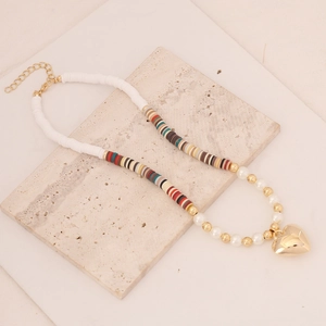 Detail of bohemian handmade clay bead necklace with pearls and gold heart pendant
