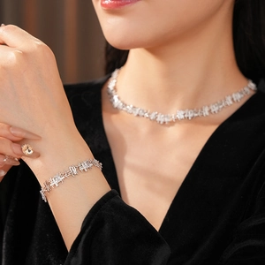 Detailed view of silver necklace and bracelet set with square zircon on female model