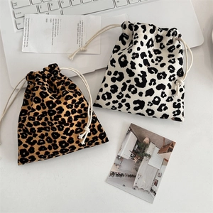 Detail of two leopard print canvas drawstring bags in brown and white on a desk