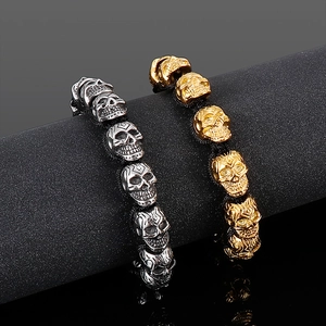 Detail of silver and gold skull bead bracelets showing punk rock metal carvings