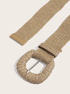 Détail d'une ceinture tressée en paille kaki avec boucle ronde et ardillon métallique