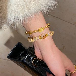 Detail of yellow crystal beaded bracelet with frosted gold beads on model's wrist