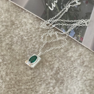 Detailed macro of a rectangular silver pendant with an emerald green oval gemstone