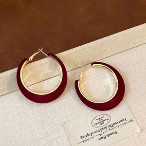 Detailed close-up of burgundy flocked C-shape earrings with elegant golden metal base
