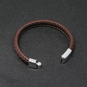 Close-up of brown braided leather bracelet with white stitching and silver magnetic clasp