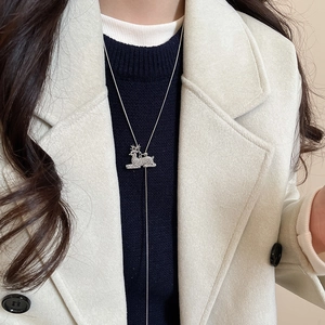 Close-up of a silver Y-shaped sweater chain featuring a crystal reindeer pendant