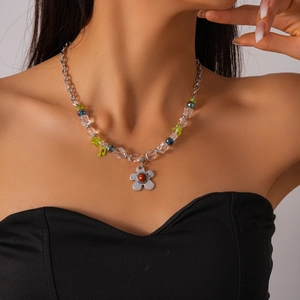 Détail du collier de perles avec breloques en verre et pendentif fleuri au cou