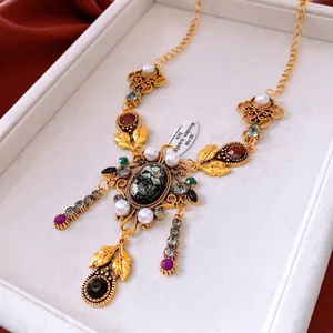 Collana vintage oro con ciondolo ovale, perle e gemme su scatola di velluto bianco