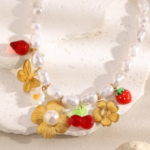 Close-up of baroque pearls necklace with gold butterfly, cherry and flower pendants