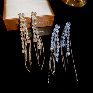 Detail of long chain tassel earrings in gold and silver set with sparkling zircon crystals