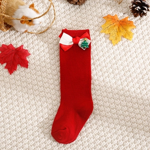 Detail of red Christmas baby knee high socks with white bow and holiday tree ornament
