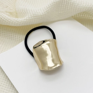 Detailed view of wide irregular curved gold metal hair cuff with a black elastic band