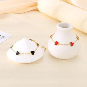 Detailed view of gold chain bracelets featuring black and red heart-shaped enamel charms