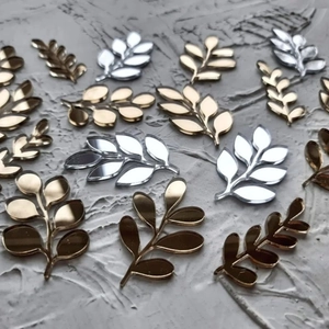 Macro detail of gold and silver leaf-shaped acrylic cake decorations with mirror finish